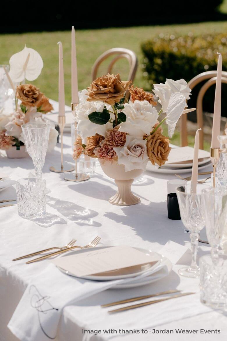 neutral wedding table decor with pale beige candles and classic flowers in vase