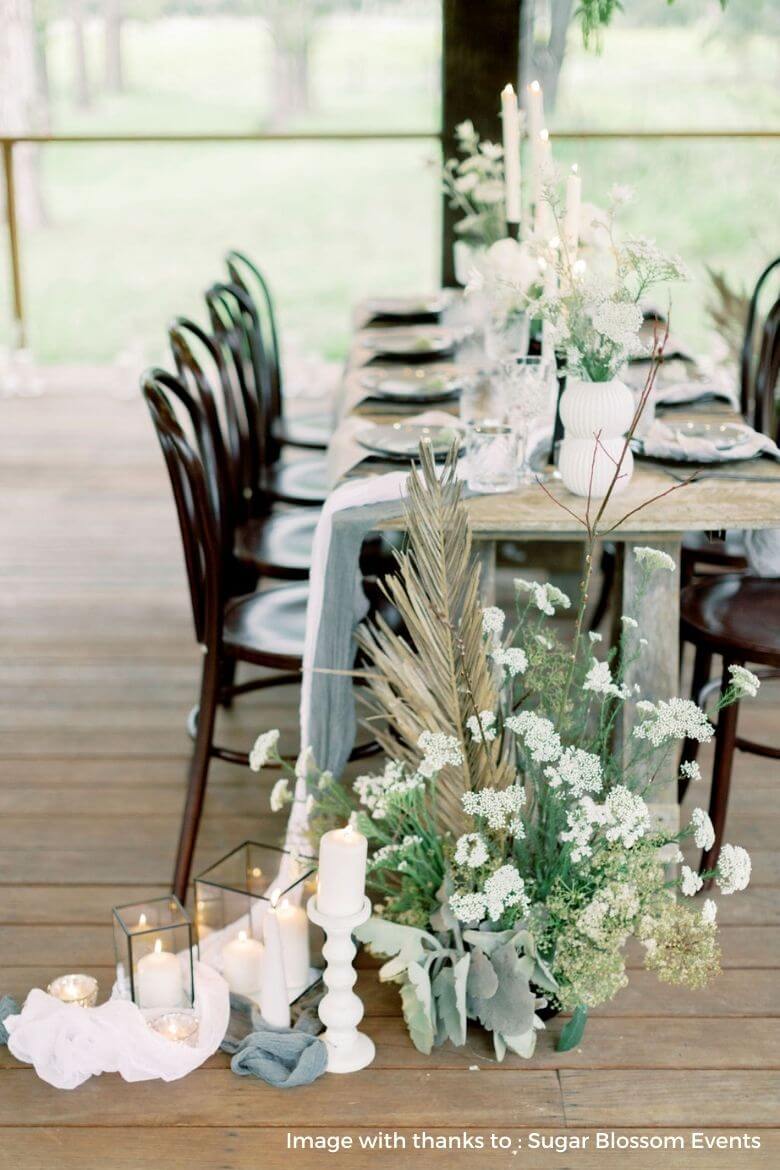 Long draped table runner with wedding candles and greenery